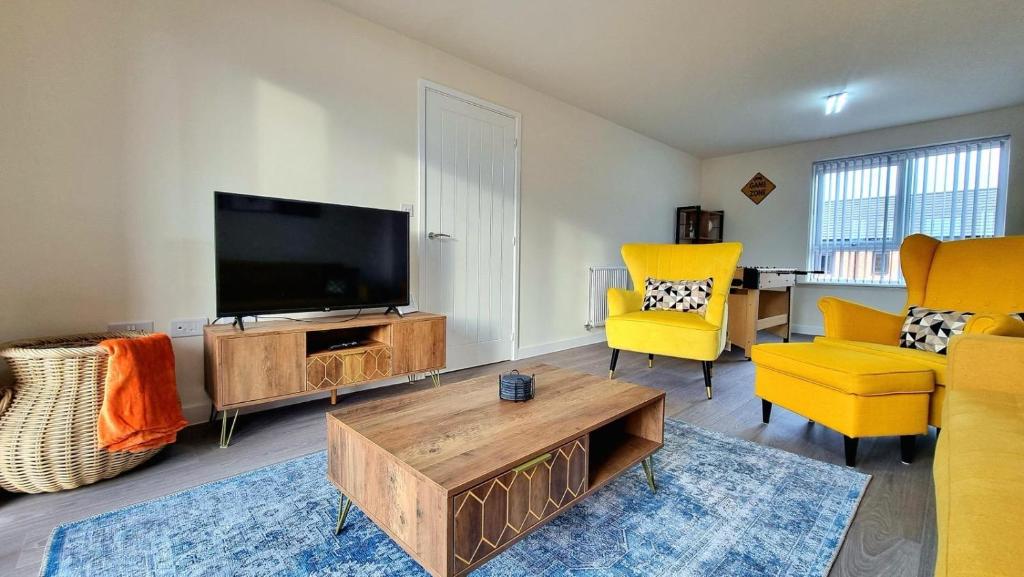 a living room with a flat screen tv and yellow chairs at Modern New Build 3-Storey Home with Parking near Leicester City Centre in Leicester