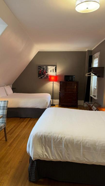a bedroom with two beds and a lamp and a chair at E-Hotel Des Grisons - Par Aneyro in Quebec City