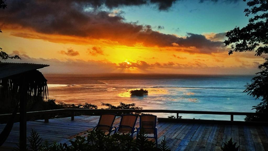 a sunset over the ocean with chairs on a deck at L'Auberge Polynésienne in Tevaitoa