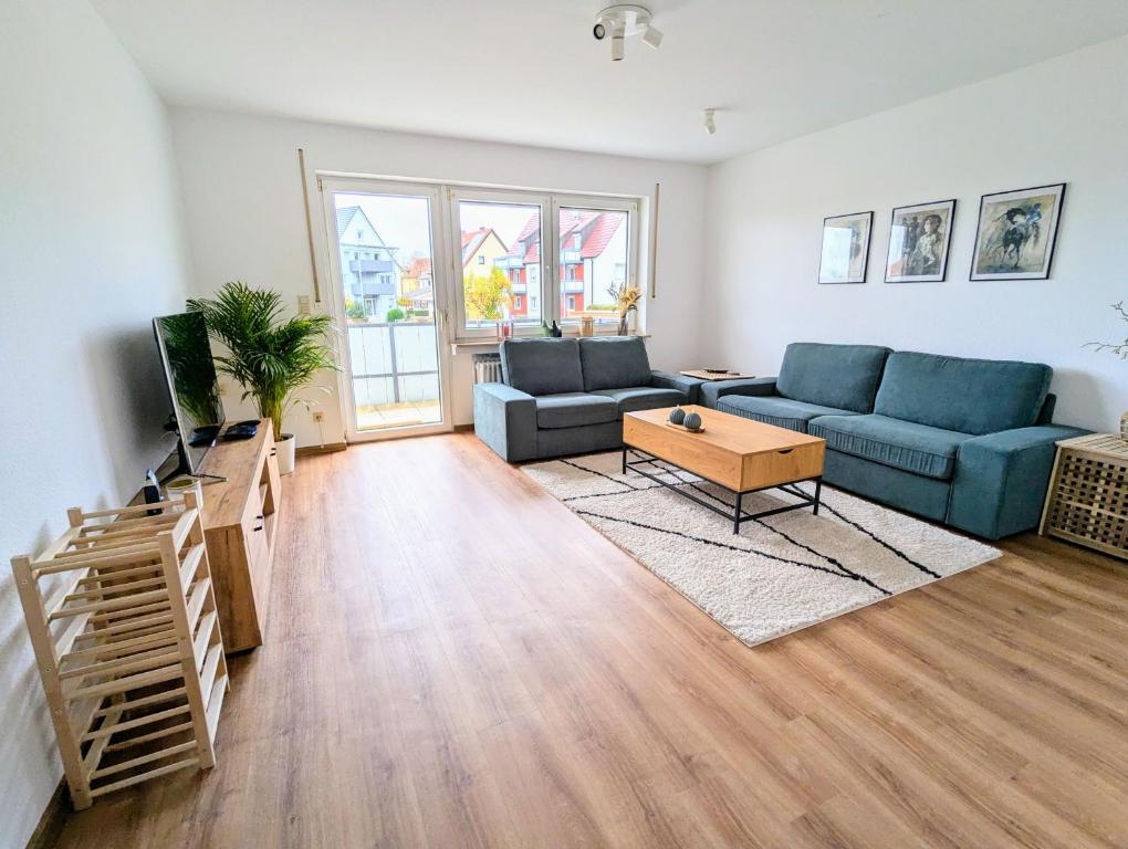 un soggiorno con un divano blu e un tavolo di Moderne und Gemütliche Stadtnahe Wohnung a Hassfurt