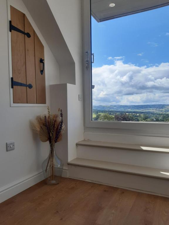ein Zimmer mit einem großen Fenster mit einer Vase aus Blumen in der Unterkunft Jasmine Cottage in Shrewsbury
