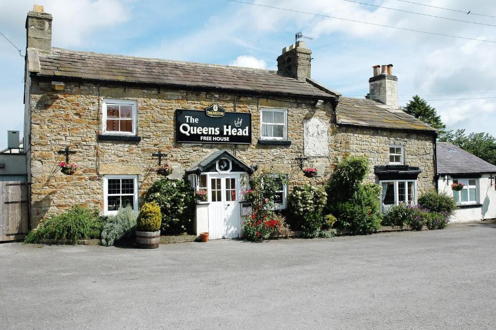 un vecchio edificio in pietra con un cartello sopra di Queens Head a Leyburn