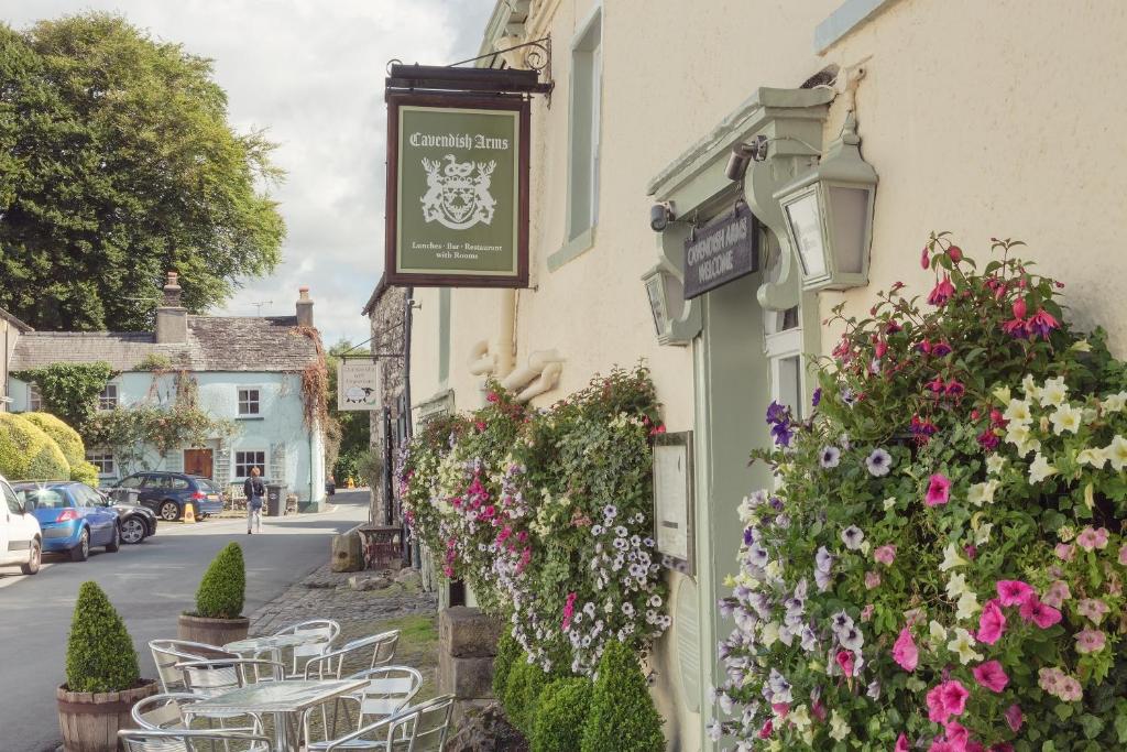 a sign on the side of a building with flowers at The Cavendish Arms in Cartmel