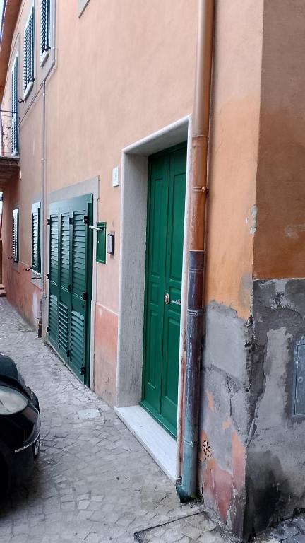 two green doors on the side of a building at Sotto la torre appartamento in Fiano Romano