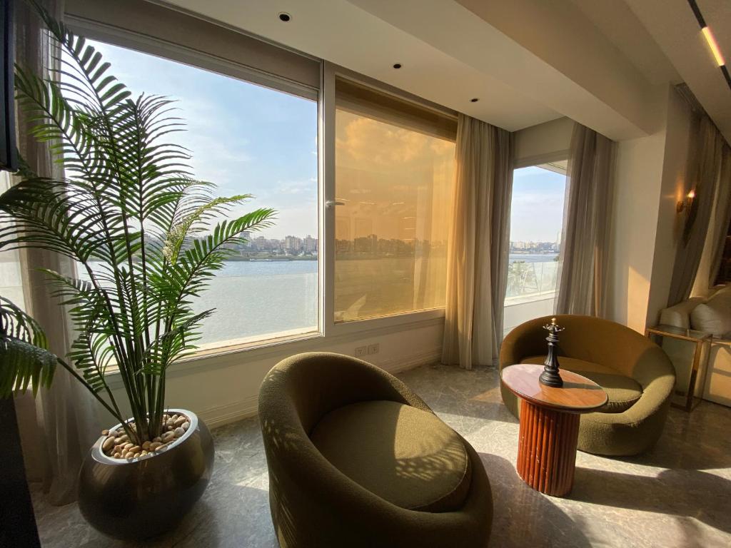 a living room with a plant and chairs and a large window at luxury apartment firist row nile view maadi cairo in Cairo