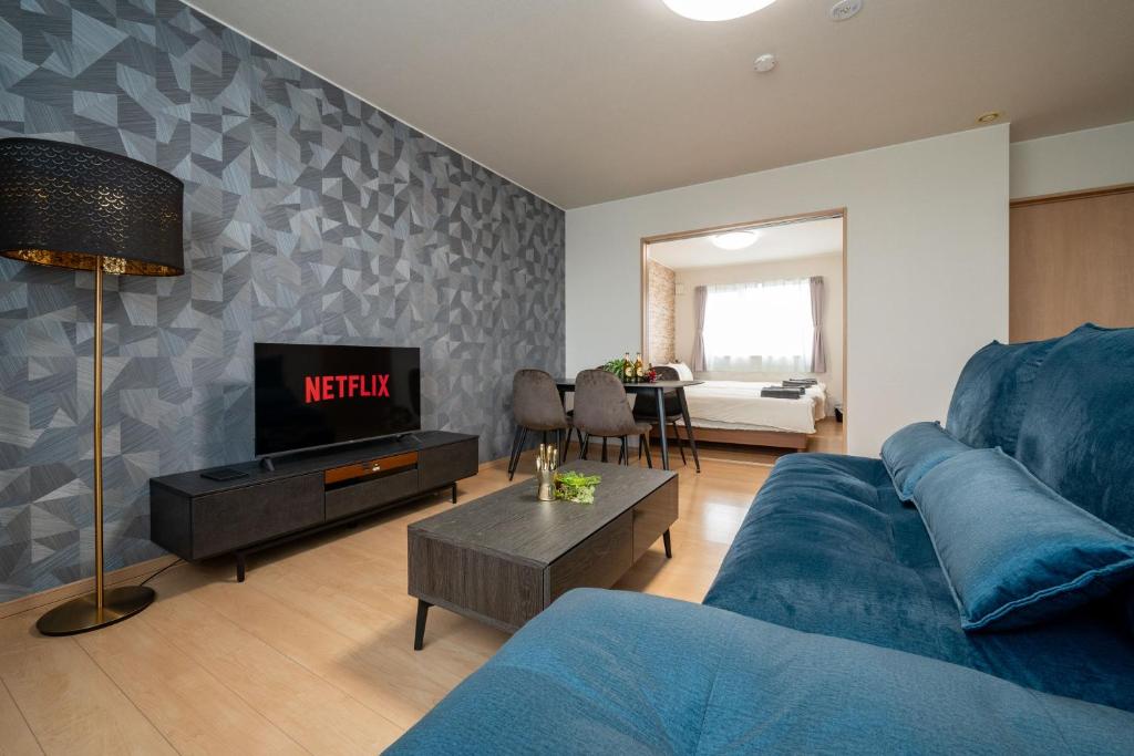 a living room with a blue couch and a tv at lapis lazuli in Kami-furano