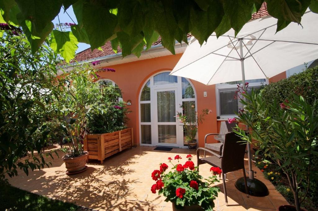 a patio with an umbrella and a chair and flowers at Villa Viola Spa&Garden in Gyula