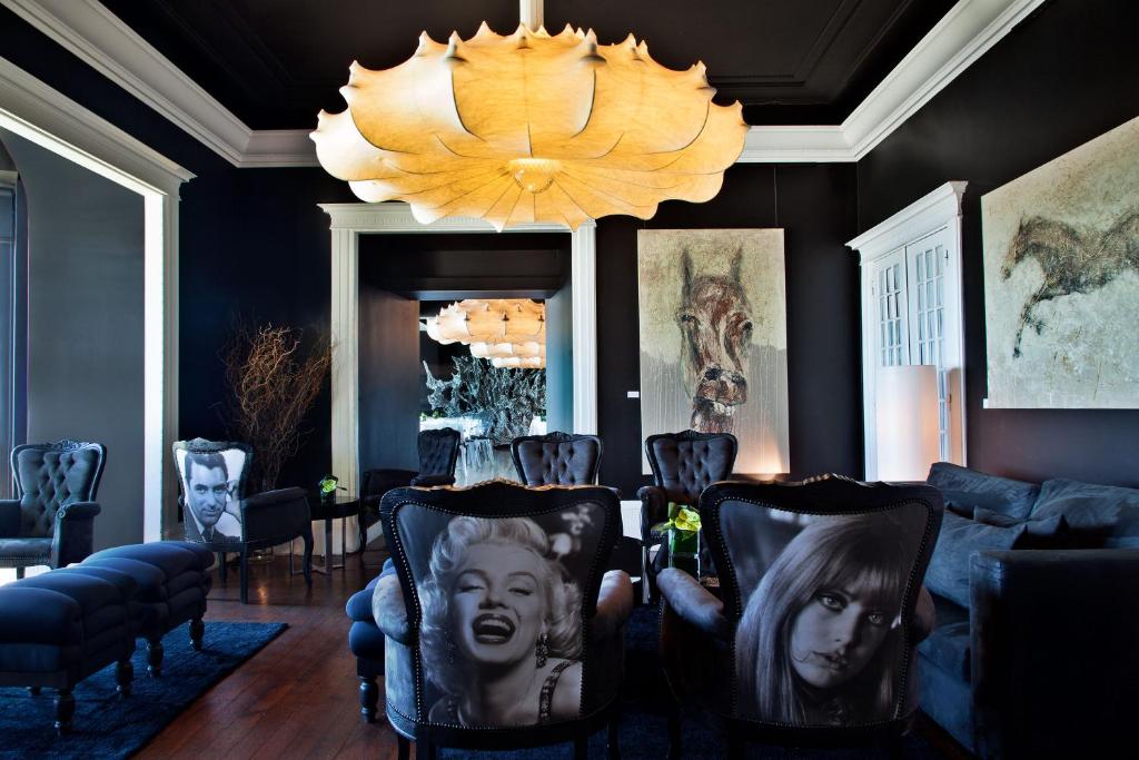 a room with a chandelier and chairs with pictures on them at Farol Hotel in Cascais