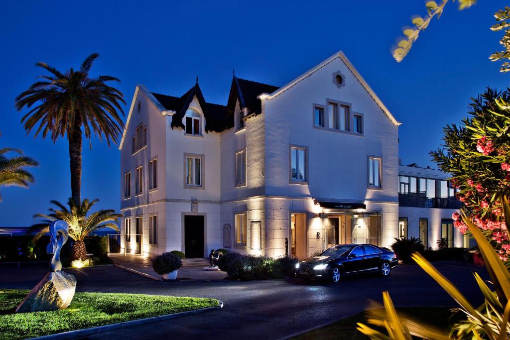 a house with a car parked in front of it at Farol Hotel in Cascais