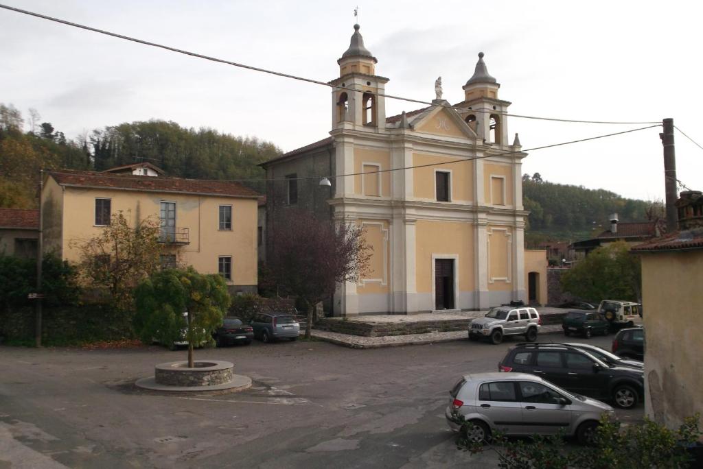 una vecchia chiesa con auto parcheggiate in un parcheggio di Casa Al Castello a Licciana Nardi
