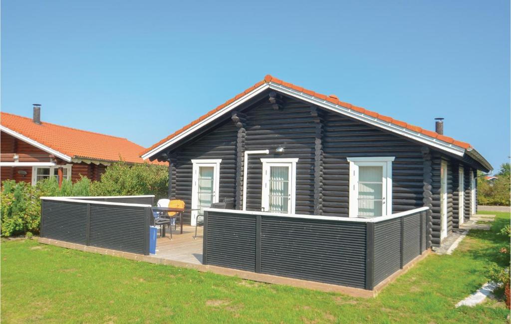 a black house with a deck in a yard at Holiday Home Marielyst Strandpark Væggerløse Ii in Marielyst