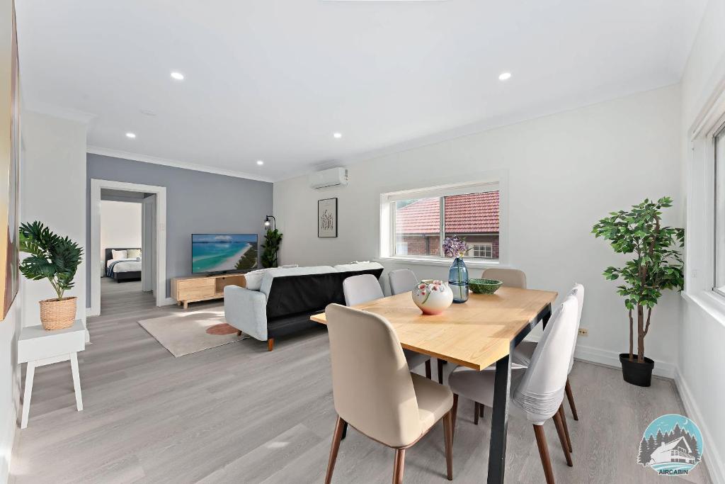a dining room and living room with a table and chairs at Stylish 4-Bed Loft in Manly Walk to Beach & Ferry in Sydney