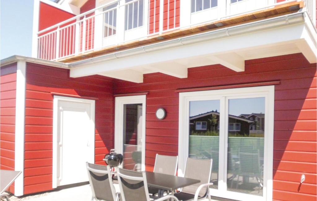 a red house with a table and chairs on the patio at Leuchtfeuer in Dagebüll