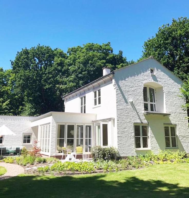 a white brick house with a porch and a yard at Het Bosch in Bergen