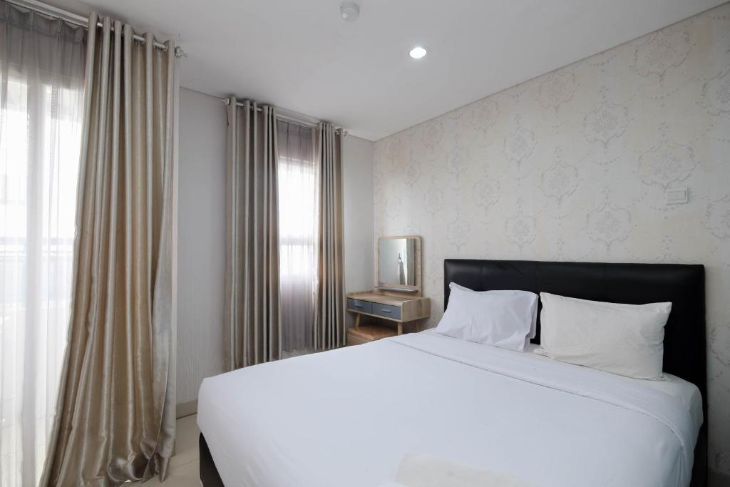 a bedroom with a large white bed and a window at Clean and Cozy 1BR Apartment with Sofabed at Atlanta Residences By Travelio in Depok
