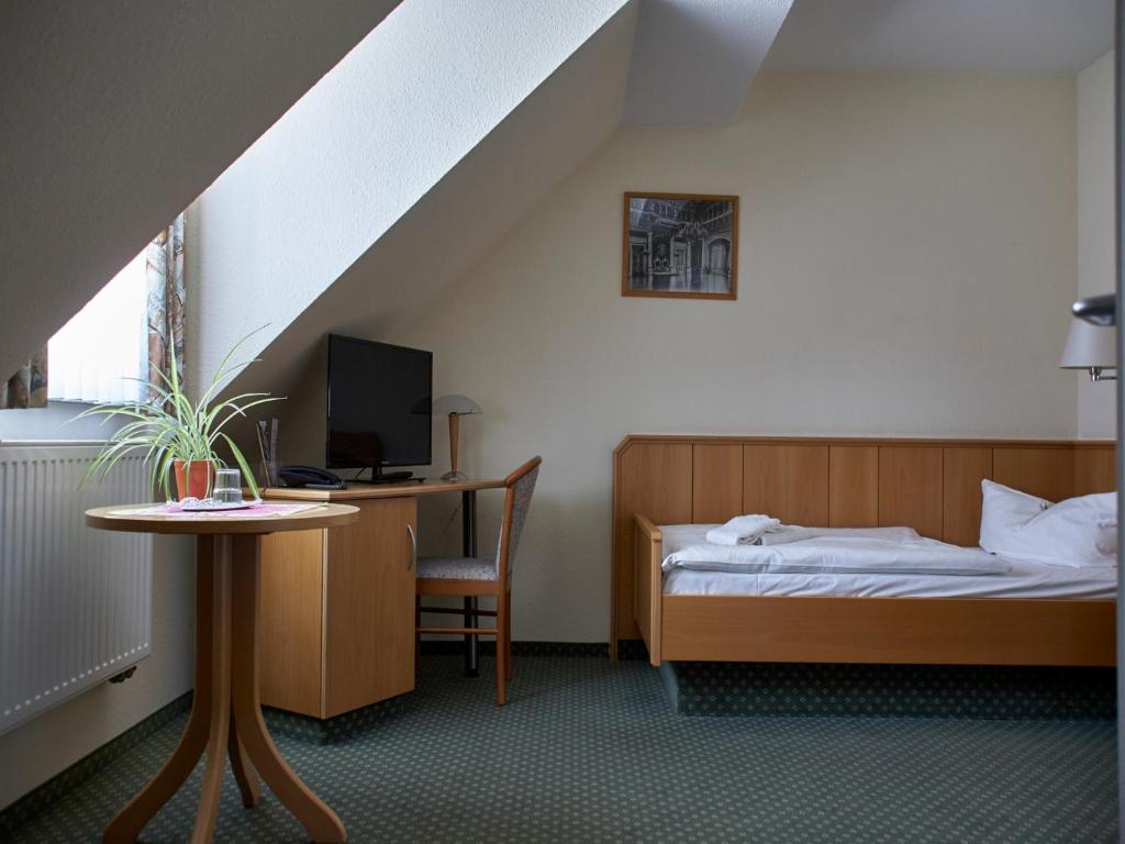 Schlafzimmer mit einem Bett und einem Schreibtisch mit einem Computer in der Unterkunft Hotel am Schloß in Schwerin