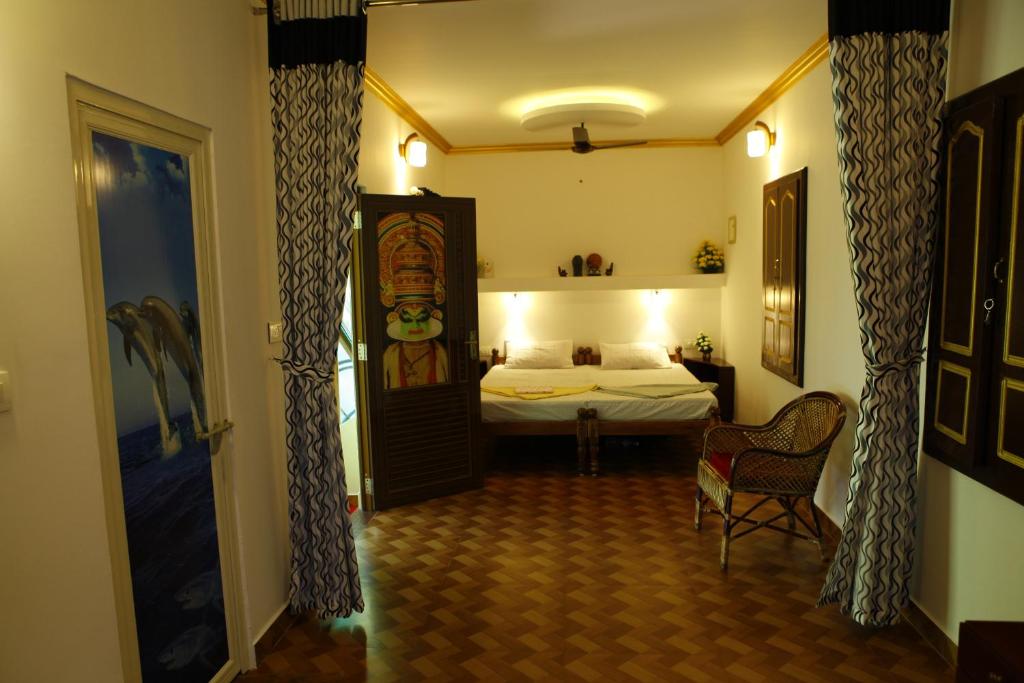 a bedroom with a bed and a chair in a room at Marari Neena Beach homestay in Mararikulam