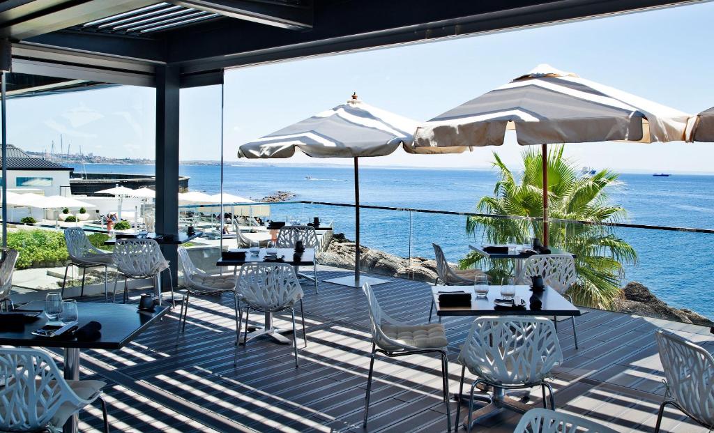 a restaurant with tables and chairs and a view of the ocean at Farol Hotel in Cascais