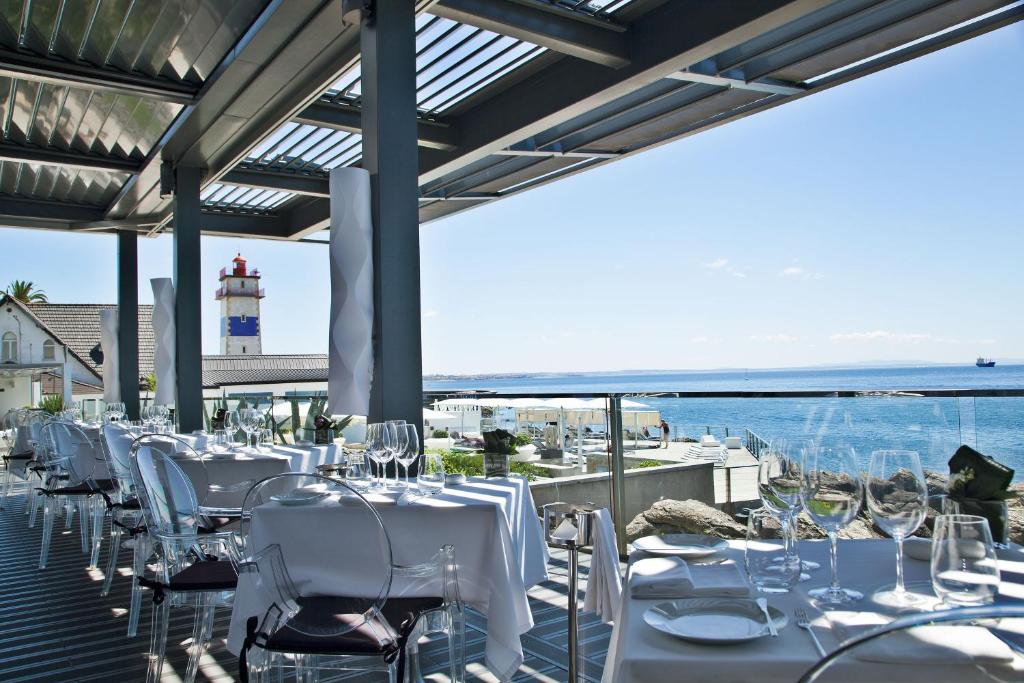 a restaurant with white tables and chairs and a lighthouse at Farol Hotel in Cascais