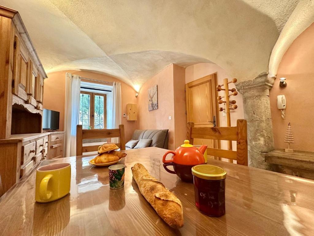 - une cuisine avec une table, une théière et du pain dans l'établissement Charmant 2 pièces avec Wi-Fi et parking à La Salle-les-Alpes - FR-1-762-53, à La Salle Les Alpes