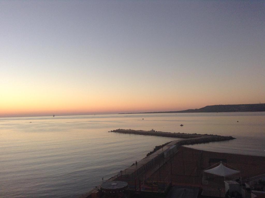 einen Sonnenuntergang über einem Wasserkörper mit einem Pier in der Unterkunft Rose Apartment in Crotone
