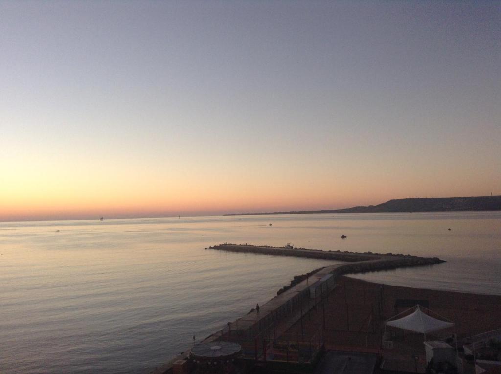 un coucher de soleil sur une étendue d'eau avec une jetée dans l'établissement Rose Apartment, à Crotone