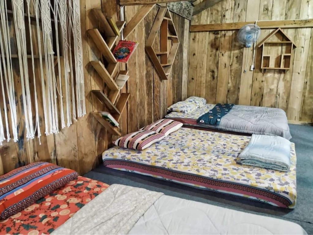 two beds in a room with wooden walls at Cô Ba Măng Đen Homestay in Kon Von Kla