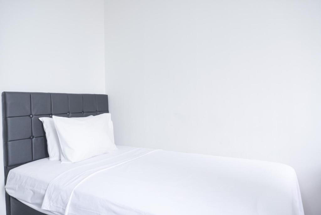 un lit blanc avec des draps et des oreillers blancs dans l'établissement Cozy Living Studio Transpark Cibubur near Shopping Center Apartment By Travelio, à Depok