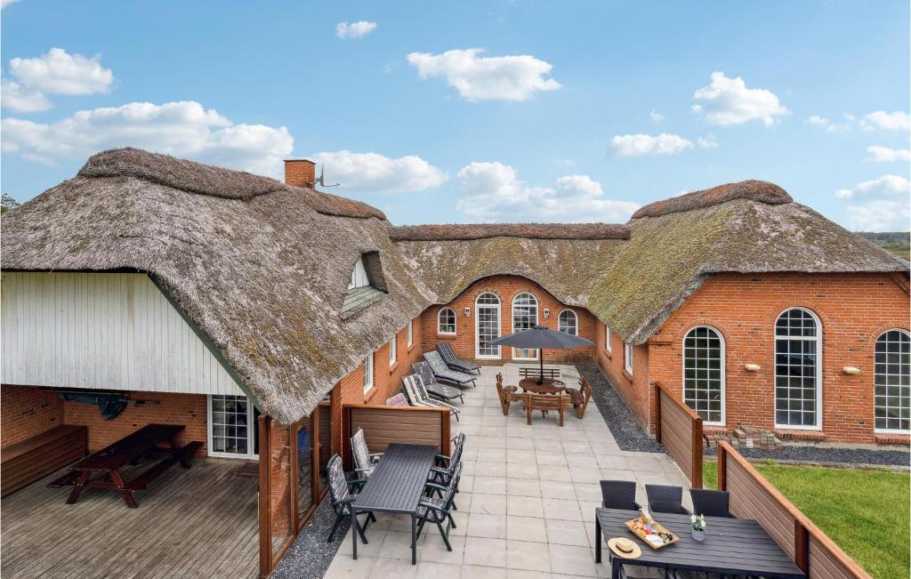 a large building with a thatched roof with a patio at Lovely Home In Rømø With Sauna in Bolilmark