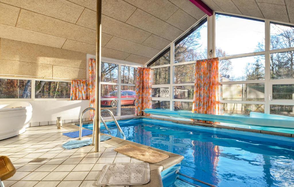 a bathroom with a swimming pool with a tub and windows at Nice Home In Glesborg With Sauna in Fjellerup Strand