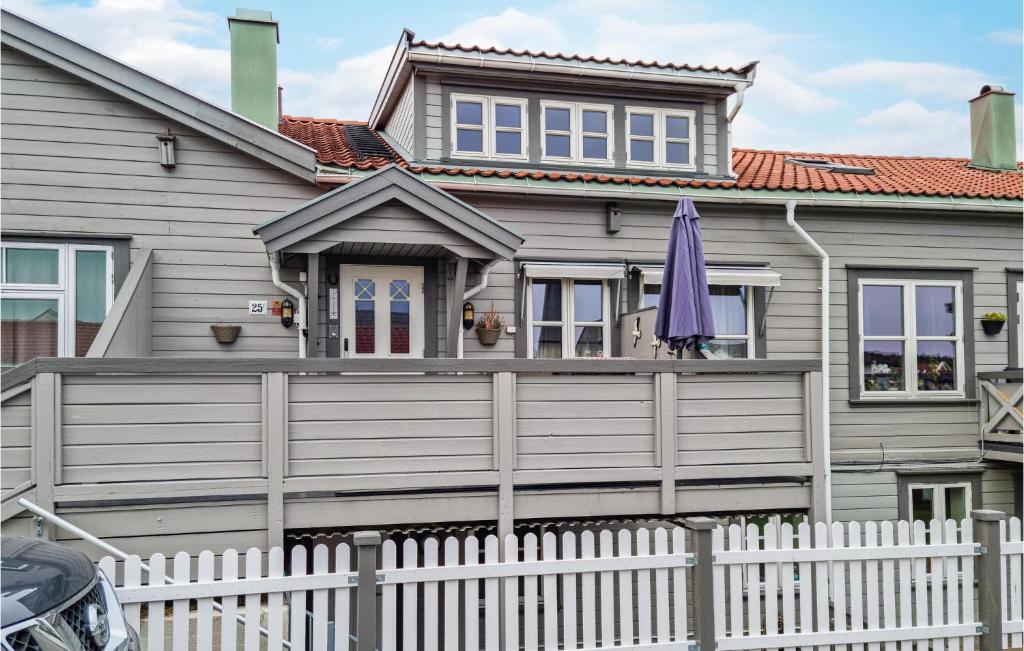 una casa con una valla blanca y una sombrilla morada en Awesome Home In Lillesand With Wifi, en Lillesand