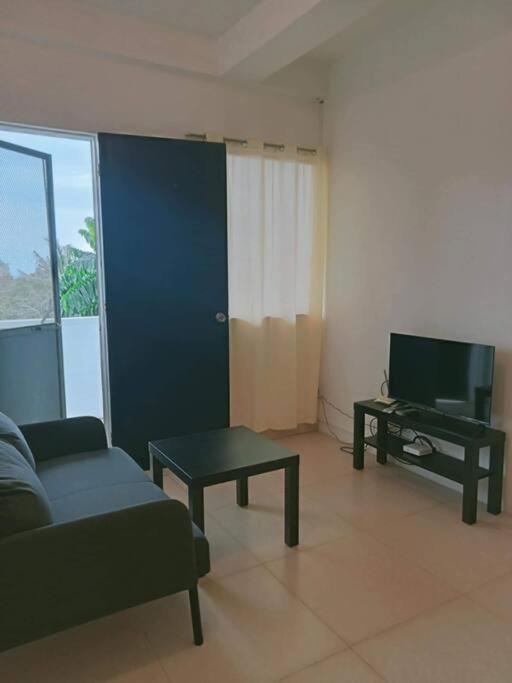 a living room with a couch and a tv and a table at Cozy 2-Bedroom Apartment in Boracay