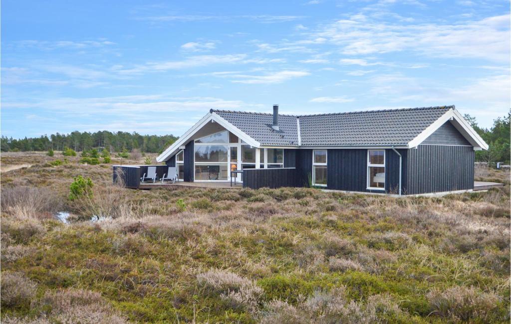 a black house on a hill in a field at Holiday Home Godthåbsvej Rømø Vi in Bolilmark