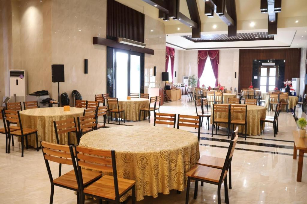 una sala banchetti con tavoli e sedie e una stanza con una stanza per non essere stata organizzata di Thong's Inn Hotel Kualanamu a Medan