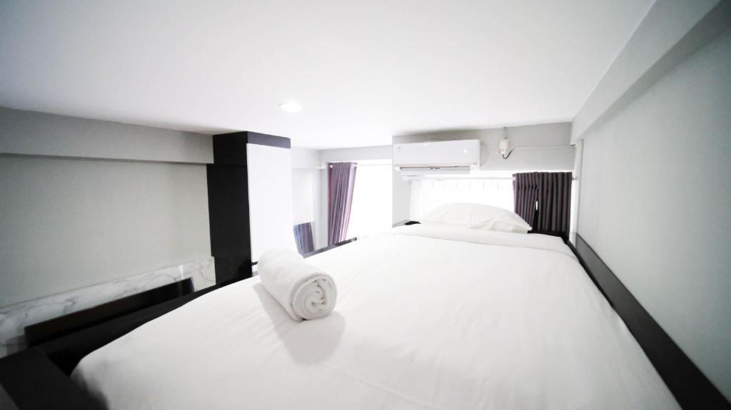 MedokanayuにあるCozy Living Studio at Bale Hinggil Apartment By Travelioの大きな白いベッドと枕が2つある寝室