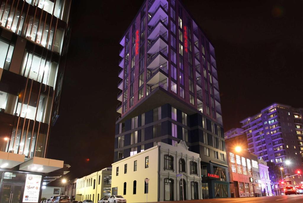 a tall building is lit up at night at Ramada Suites By Wyndham Victoria Street West in Auckland