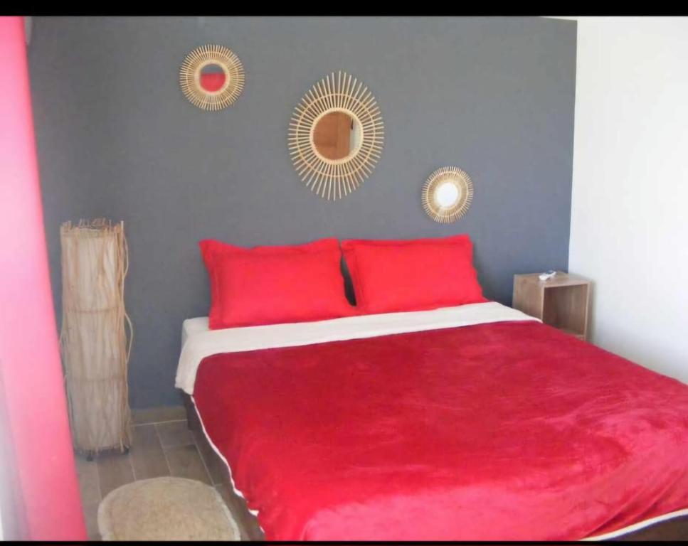 a bedroom with a red bed with two mirrors on the wall at Le Longani 974 in Saint-Pierre