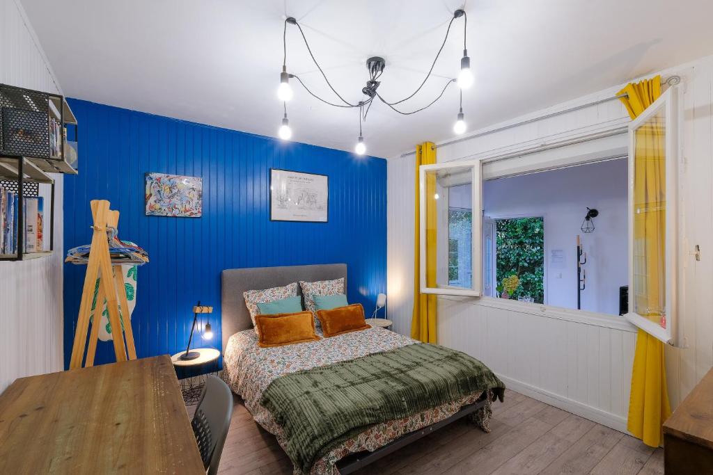- une chambre bleue avec un lit et une table en bois dans l'établissement La terrasse de M.Hulot - 1 chambre, à Saint-Nazaire