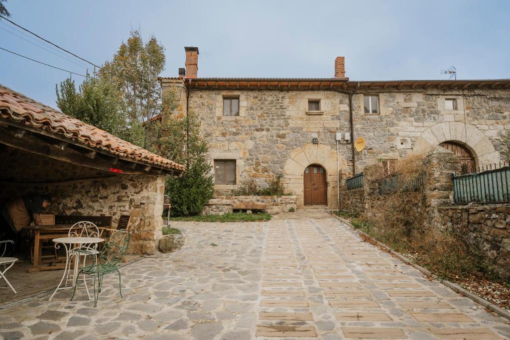 un antico edificio in pietra con tavolo e porta di La Casa Del Diezmo De La Montaña a Redondo