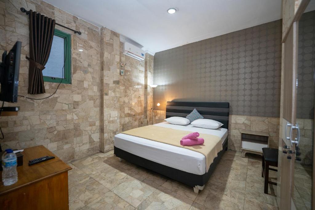 a bedroom with a bed with two pink towels on it at WABS Syariah in Bandung