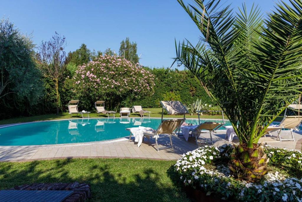 a pool with chairs and a palm tree in a yard at Apartment Villa Kennedy - Bob in Sirmione