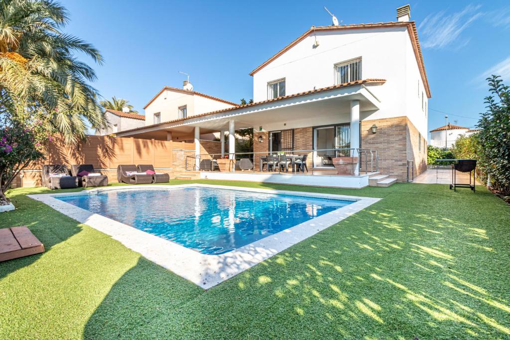 a villa with a swimming pool in front of a house at Jouvacations Villa Sun Pani in Empuriabrava