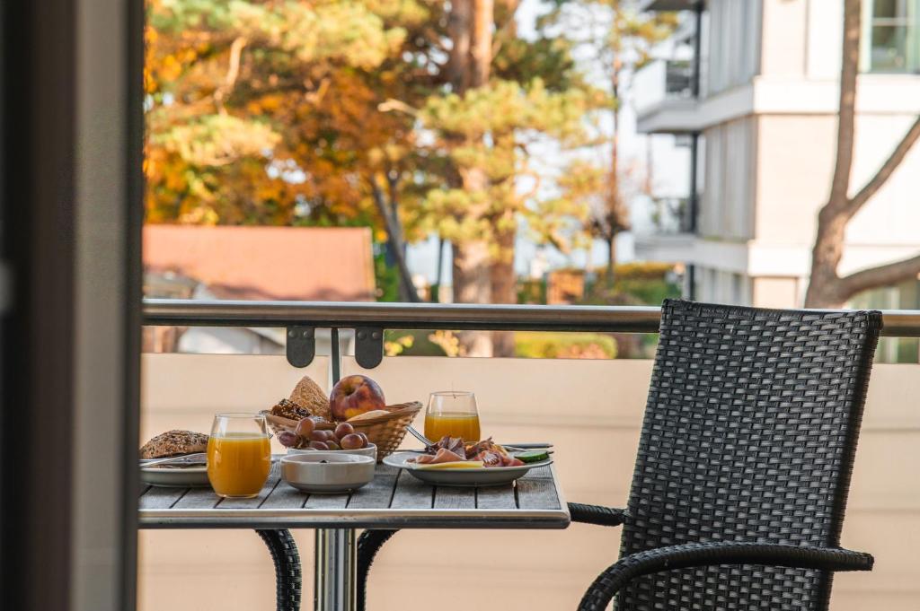 a table with a plate of food and two glasses of orange juice at Arkona Strandresidenzen in Binz