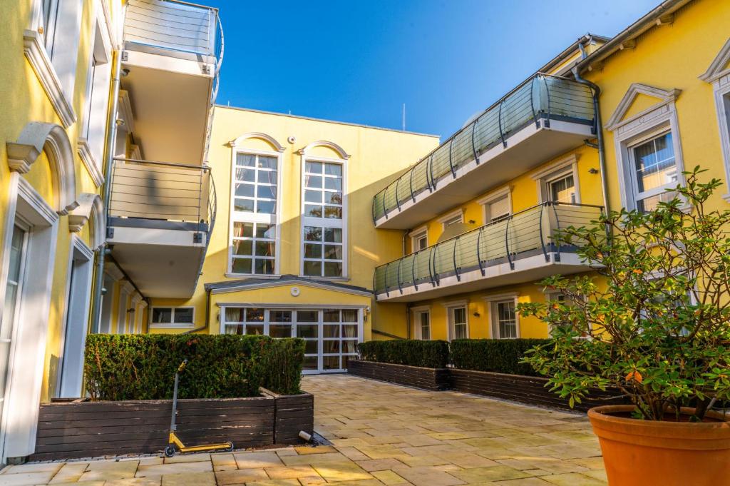 a yellow building with balconies and a courtyard at Arkona Strandresidenzen in Binz