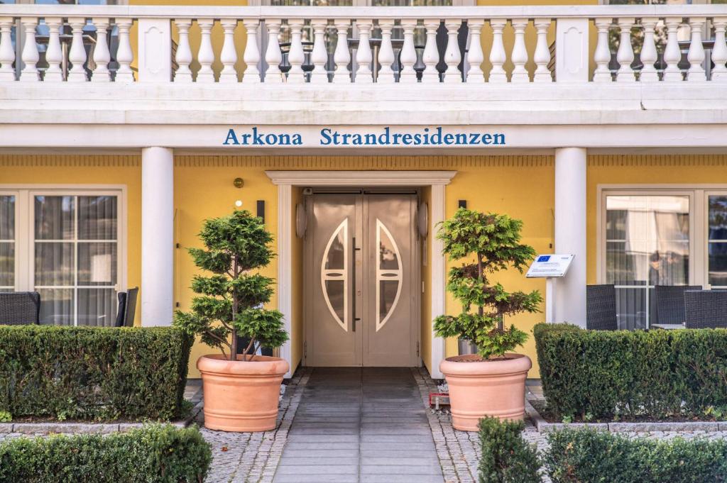 a front door of a yellow building with potted trees at Arkona Strandresidenzen in Binz