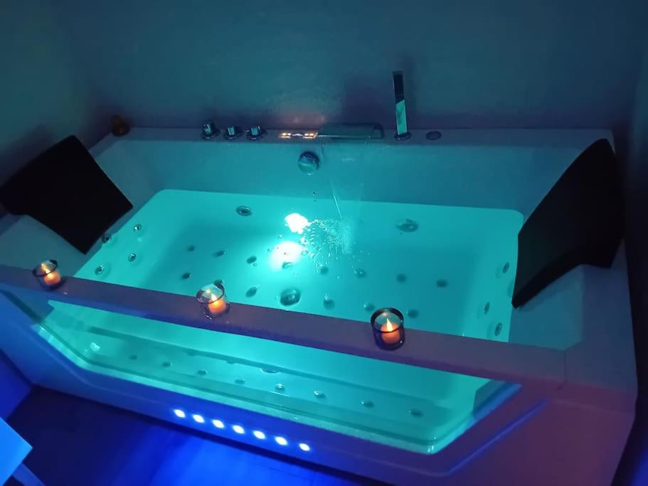 - une baignoire verte avec des lumières dans la chambre dans l'établissement Le Paradis Secret Plage et Balneo, à Gouville-sur-Mer