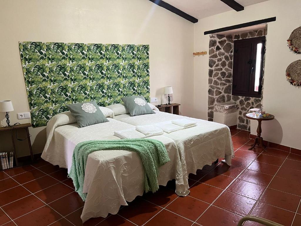 - une chambre avec un lit orné d'une peinture verte sur le mur dans l'établissement Ceclavinn Casa Rural, à Ceclavín