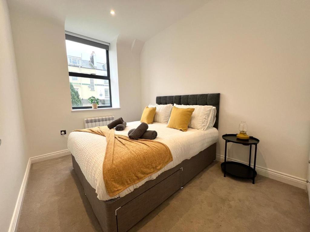 Un dormitorio con una cama con almohadas amarillas y una ventana. en Richmond Mews by Staytor Accommodation, en Exeter