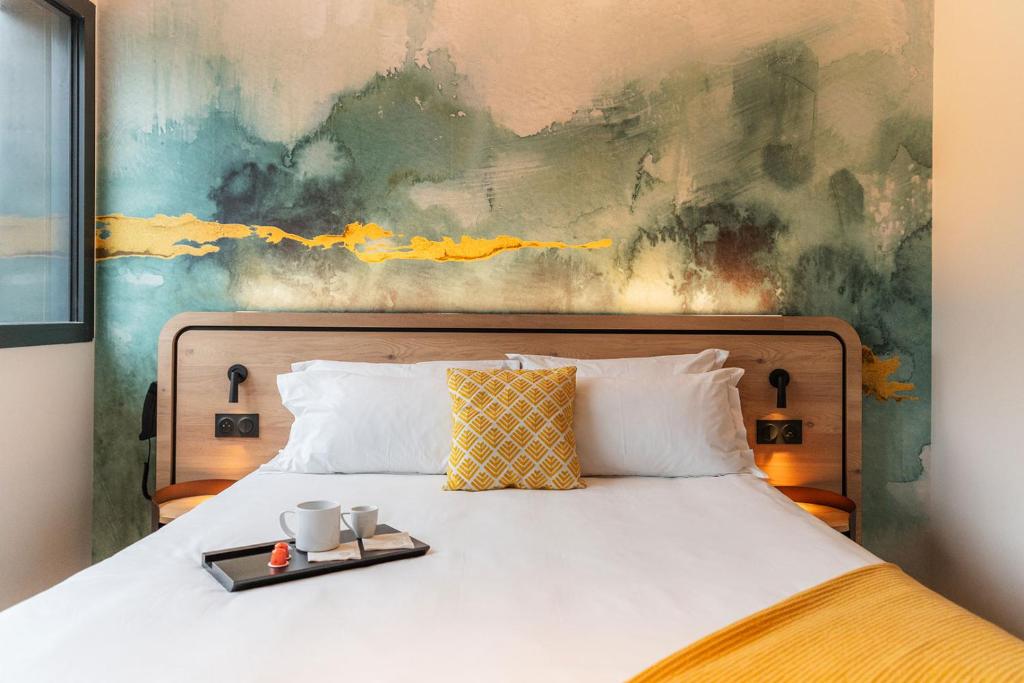ein Bett mit einem Tablett mit zwei Tassen drauf in der Unterkunft La Reposée Hôtel Restaurant Spa in Liffré