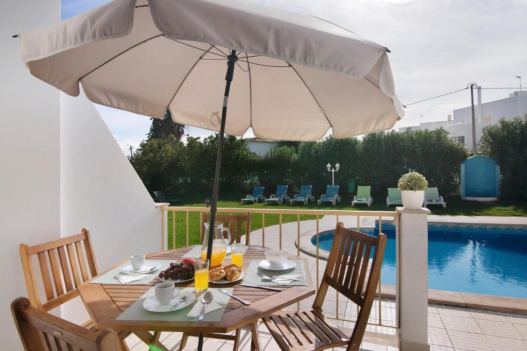 einen Tisch mit einem Sonnenschirm neben einem Pool in der Unterkunft Villa Martina in Albufeira